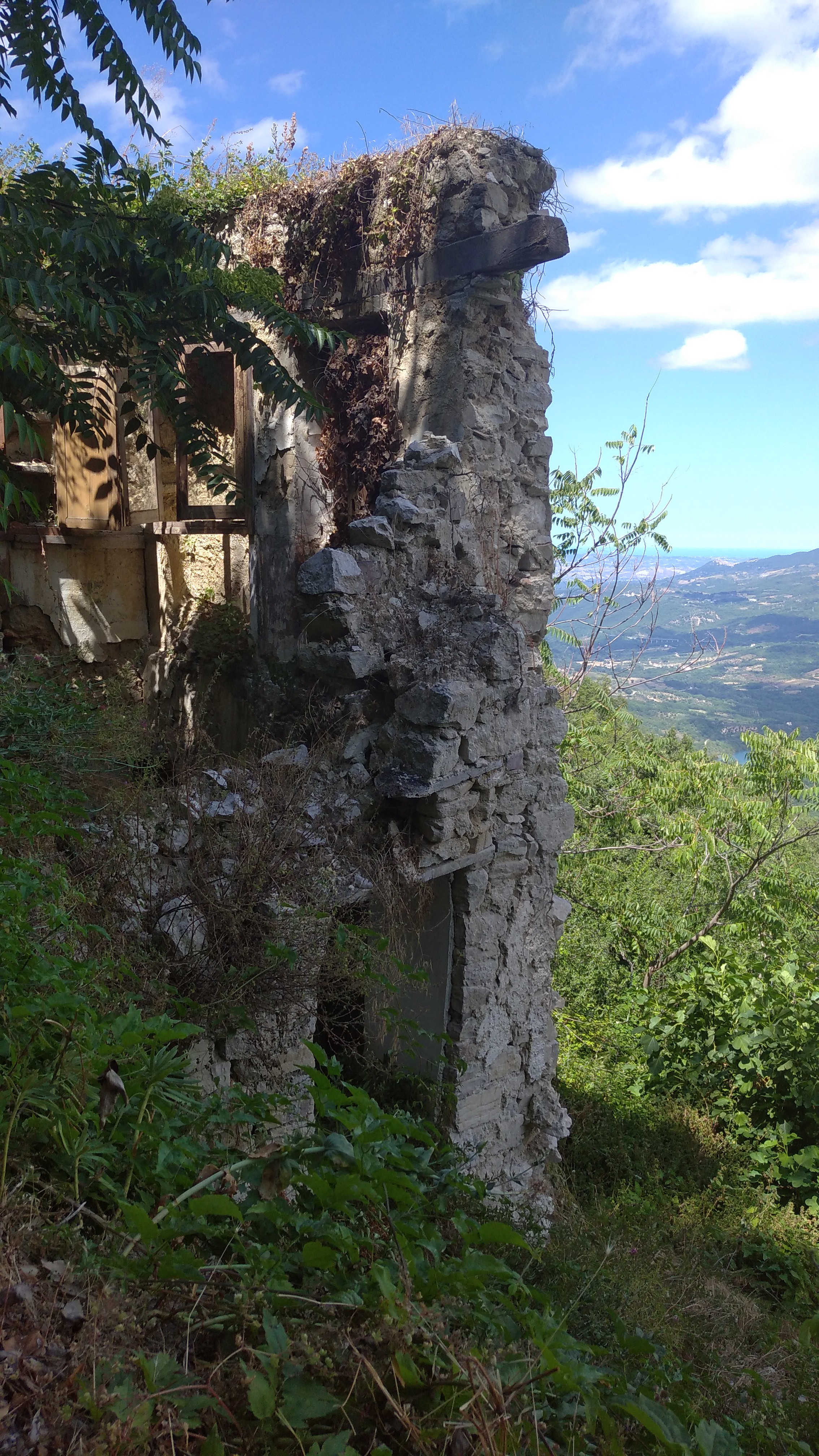 A Buona Contemporanea art exhibition card pinned to an ancient stone wall in Buonanotte