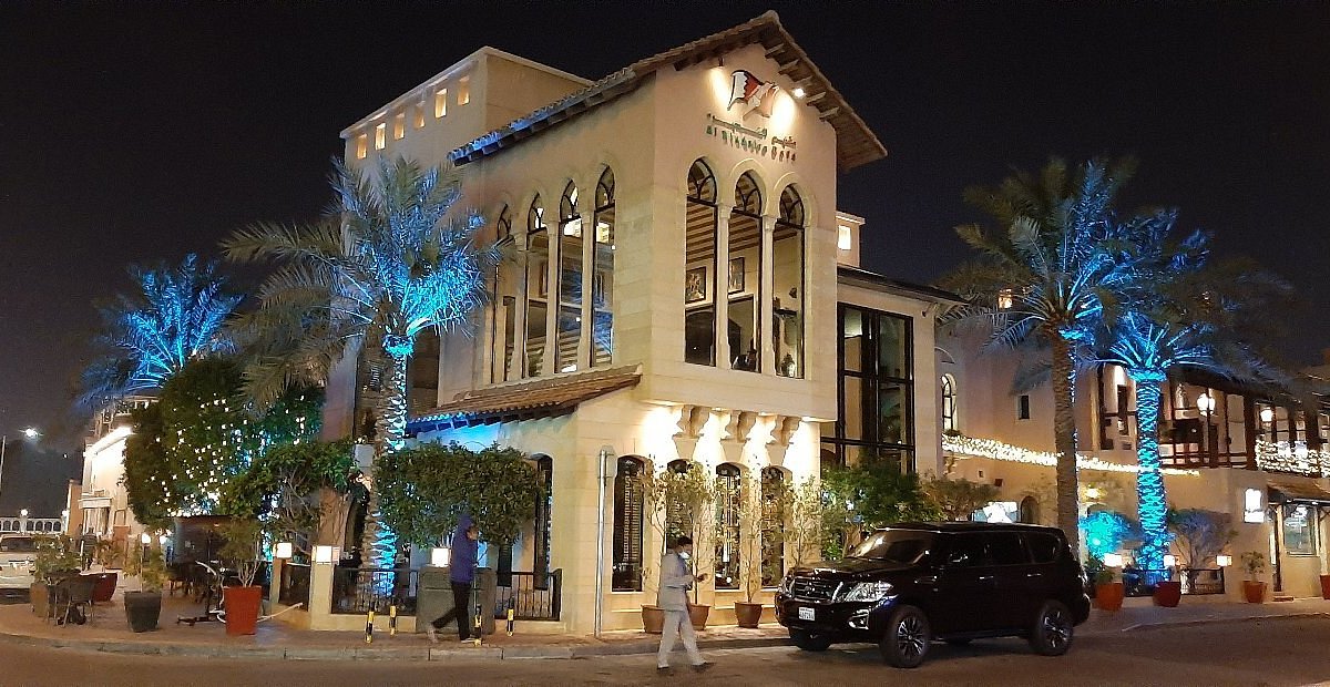 Barrio de Adliya en Manama por la noche, con terrazas de restaurantes, asientos al aire libre y el skyline de la ciudad del Golfo
