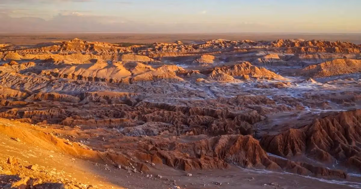 Geformte Felsformationen und Dünen im Valle de la Luna in der chilenischen Atacama-Wüste bei Sonnenuntergang