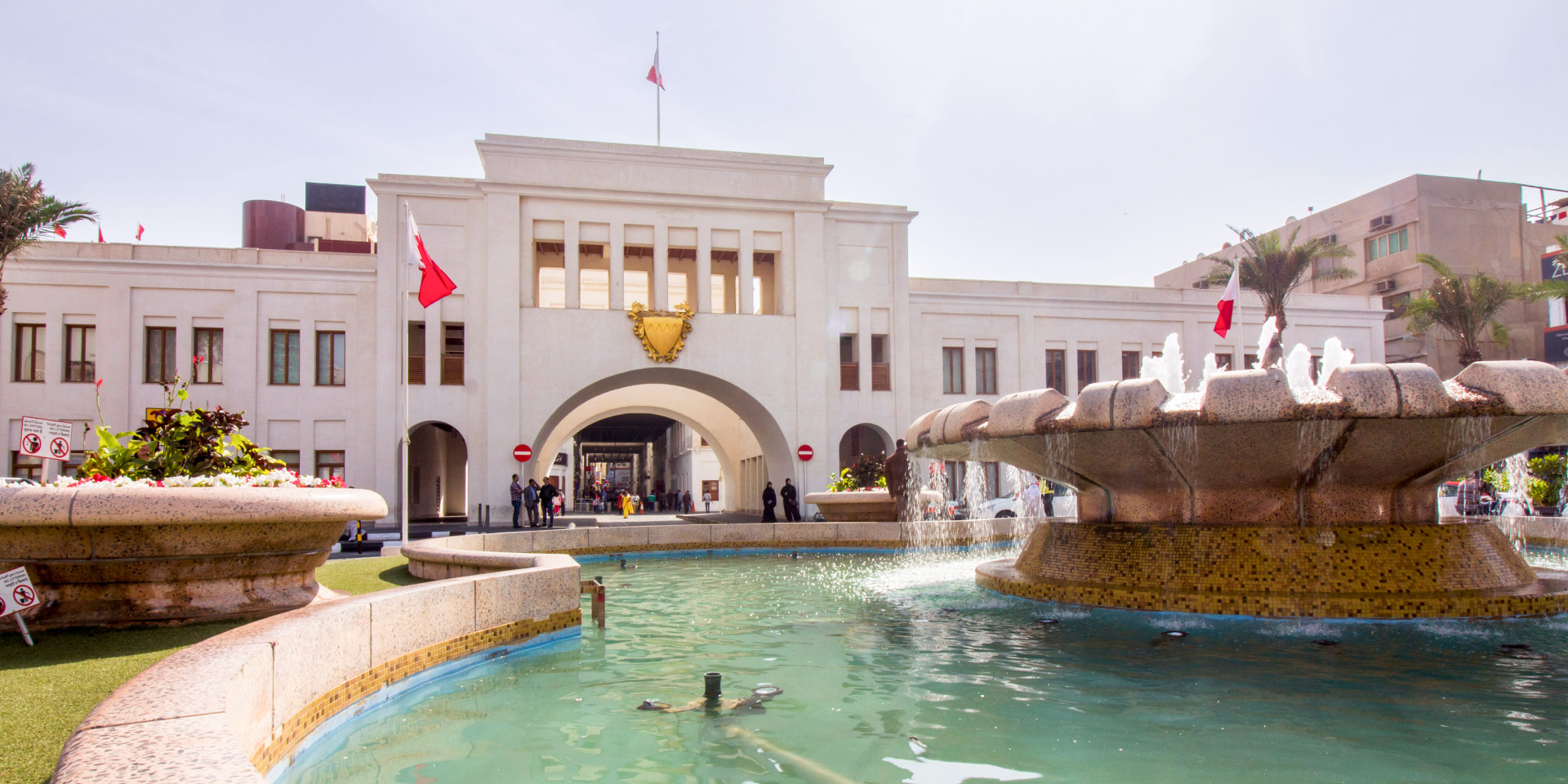 Puerta de Bab Al Bahrain y entrada al zoco en Manama, con compradores y puestos de mercado tradicional