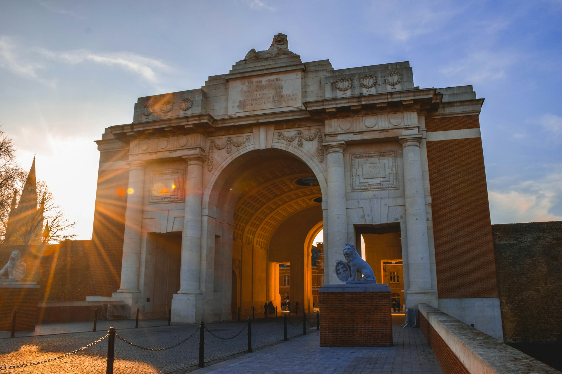 Menin Gate -muistokaari Ypresissä hämärässä, kaiverrettu 54 896 kadonneen ensimmäisen maailmansodan sotilaan nimellä, Last Post -seremonian yleisö alla