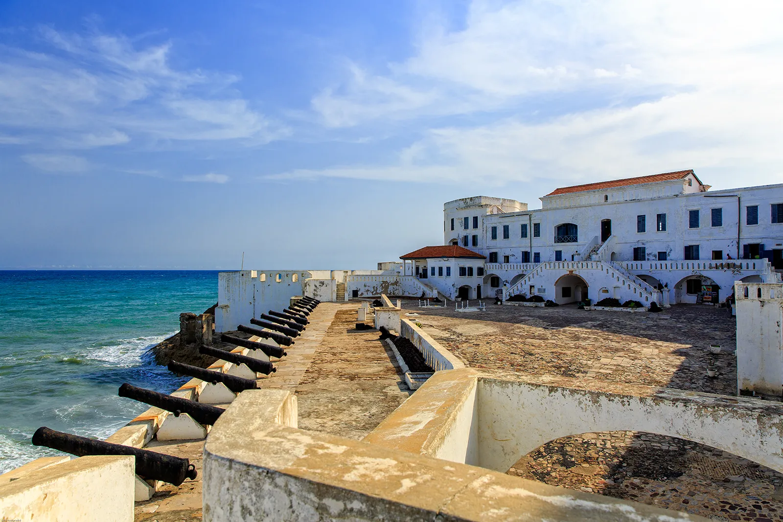 Die weiß getünchten Festungsmauern von Cape Coast Castle über Fischerbooten an der Atlantikküste Ghanas