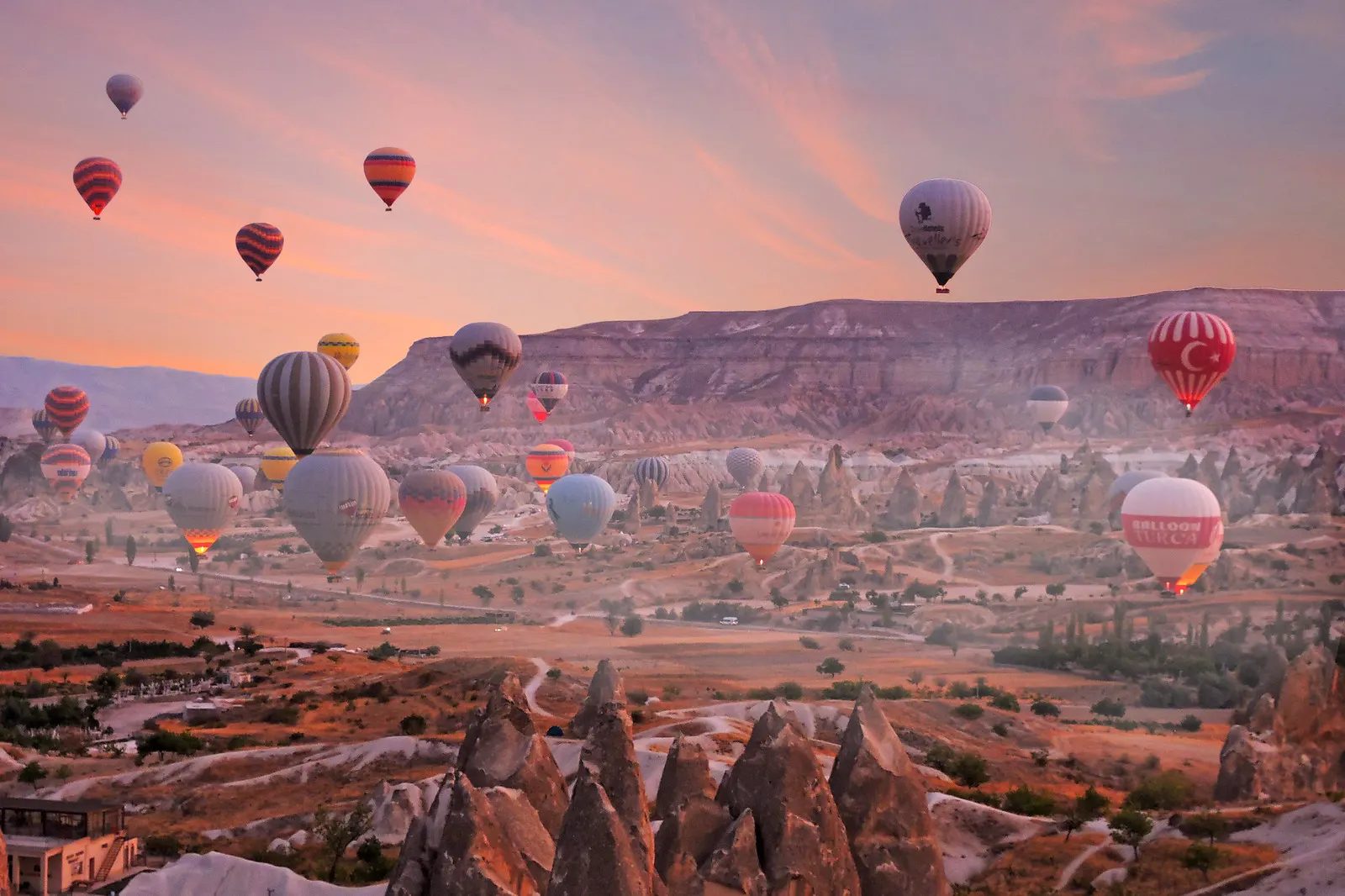 Des dizaines de montgolfières au-dessus des vallées de cheminées de fées de Cappadoce, Turquie, au lever du soleil