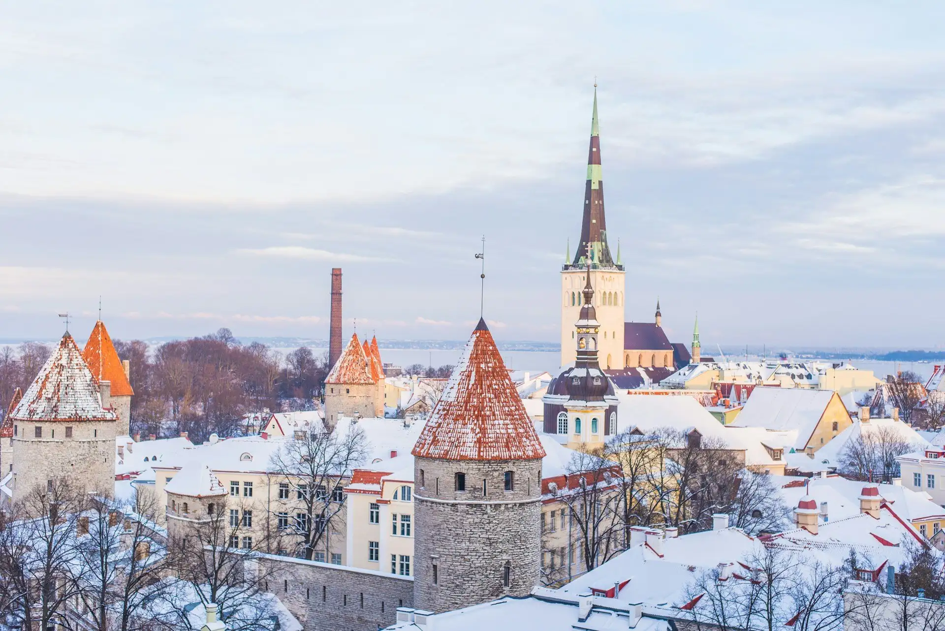 Mittelalterliche Türme und die Stadtmauer der Tallinner Altstadt bei Dämmerung mit einem frostbedeckten Dächermeer dahinter, Estland