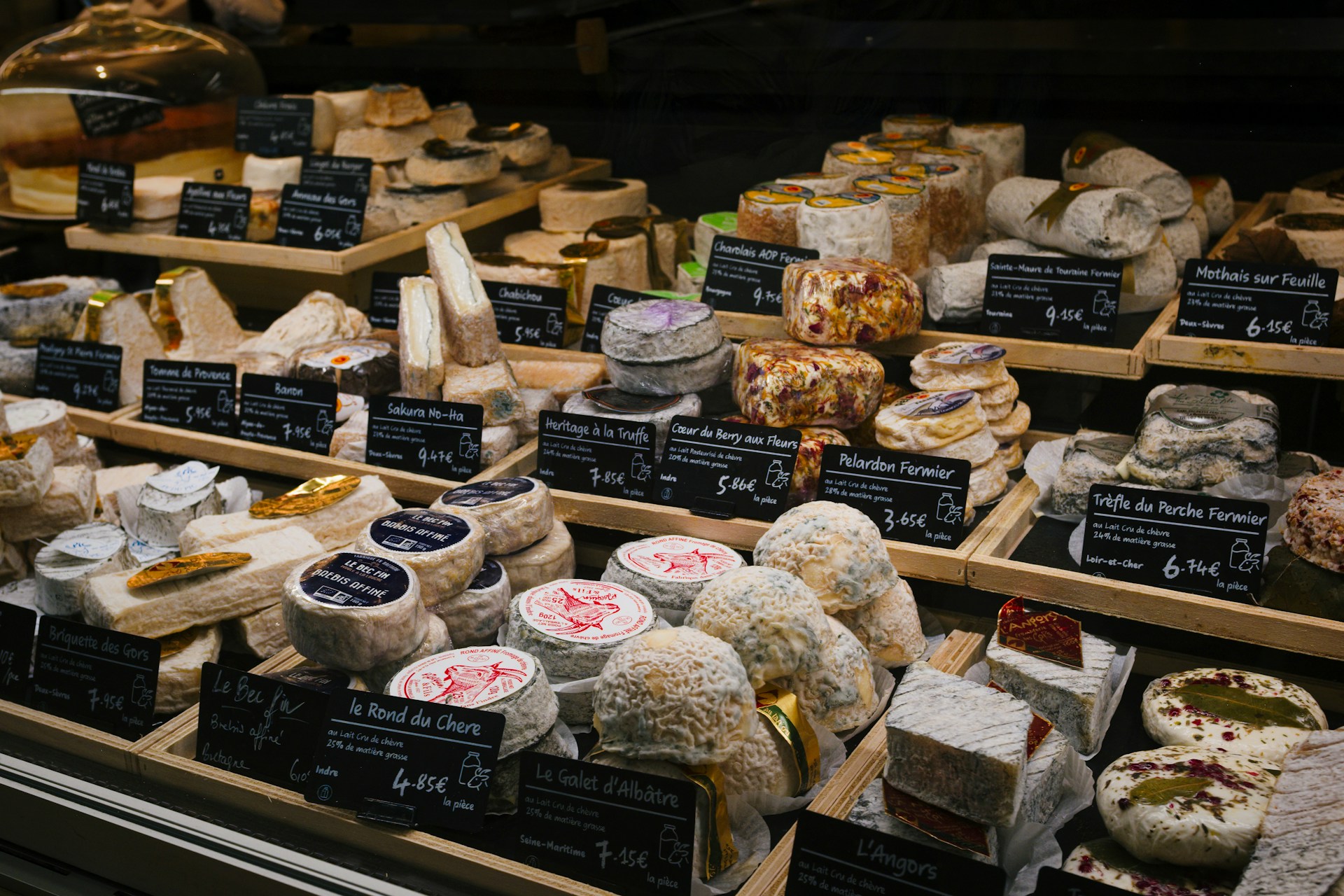 Französischer Käsemarktstand mit Laiben von Comté, Camembert, Roquefort und regionalen Käsen auf einem Markttisch