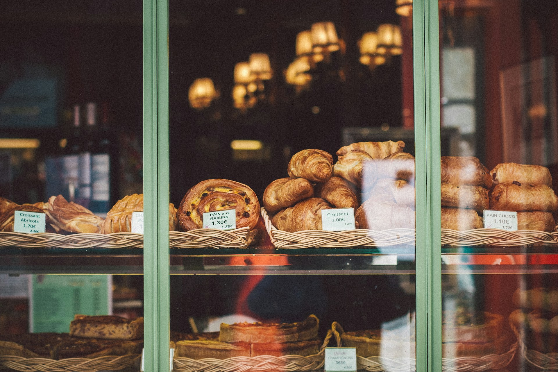 Frische französische Croissants und Baguettes in einer Pariser Bäckerei mit goldenen Gebäckstücken in einem Weidenkorb auf einer Marmorplatte