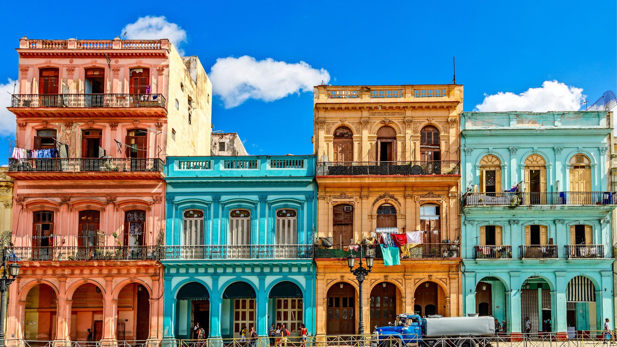 Classic American car passing colorful colonial buildings on the Malecon waterfront in Havana, Cuba
