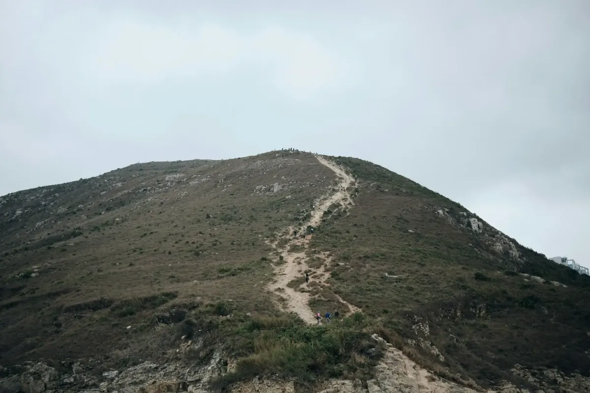Een wandelpad dat een met gras begroeide heuvel beklimt in het platteland van Hongkong