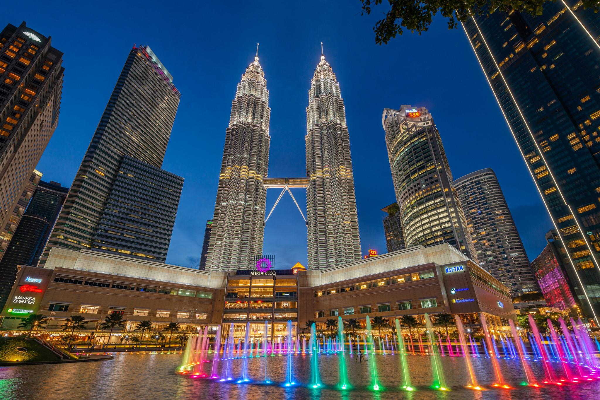 Kuala Lumpur Petronas Twin Towers illuminated at night above Suria KLCC park and its fountains