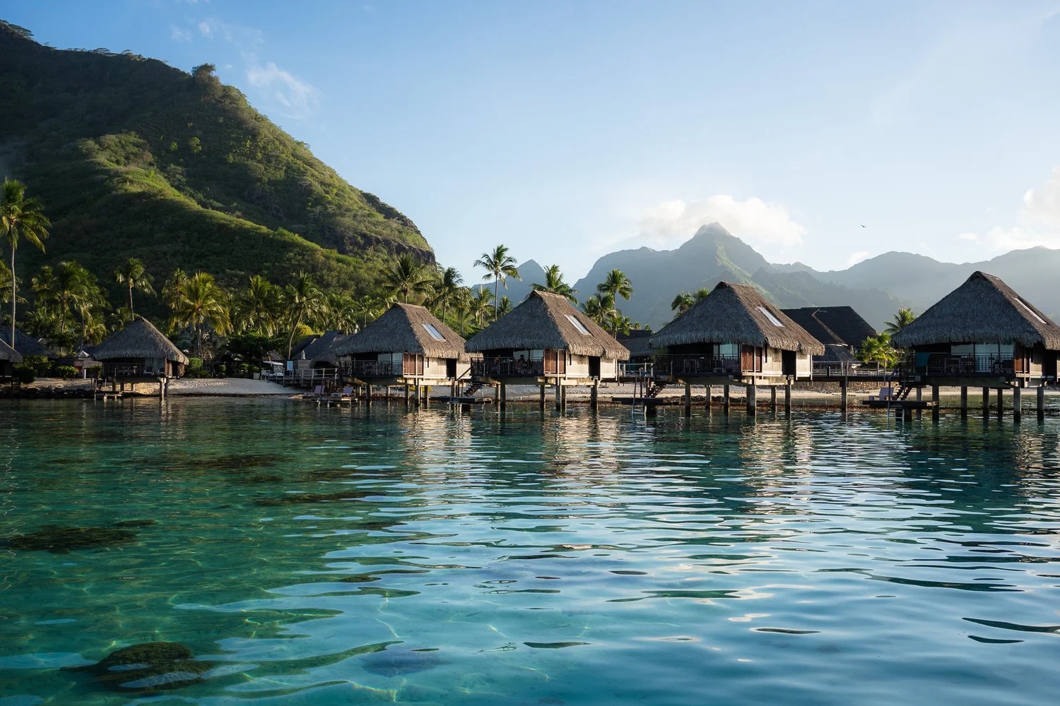 Overwater bungalows and turquoise lagoon at Moorea, French Polynesia, with jagged green peaks behind