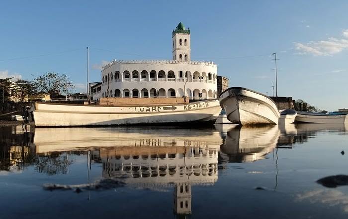 Paseo marítimo de la Cornisa de Moroni con el minarete de la mezquita Badjanani y dhows de madera en el puerto viejo