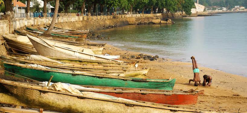 Fishing boats along the harbor in São Tomé city with the Fortaleza de São Sebastião in the background