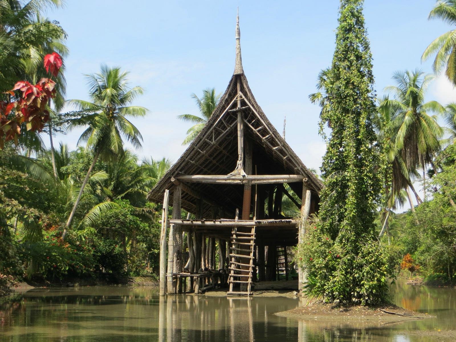 A traditional Haus Tambaran spirit house with carved totems on the banks of the Sepik River