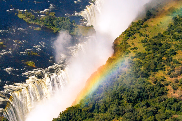 Rainbow over Victoria Falls with spray rising from the Zambezi gorge on the Zimbabwe side
